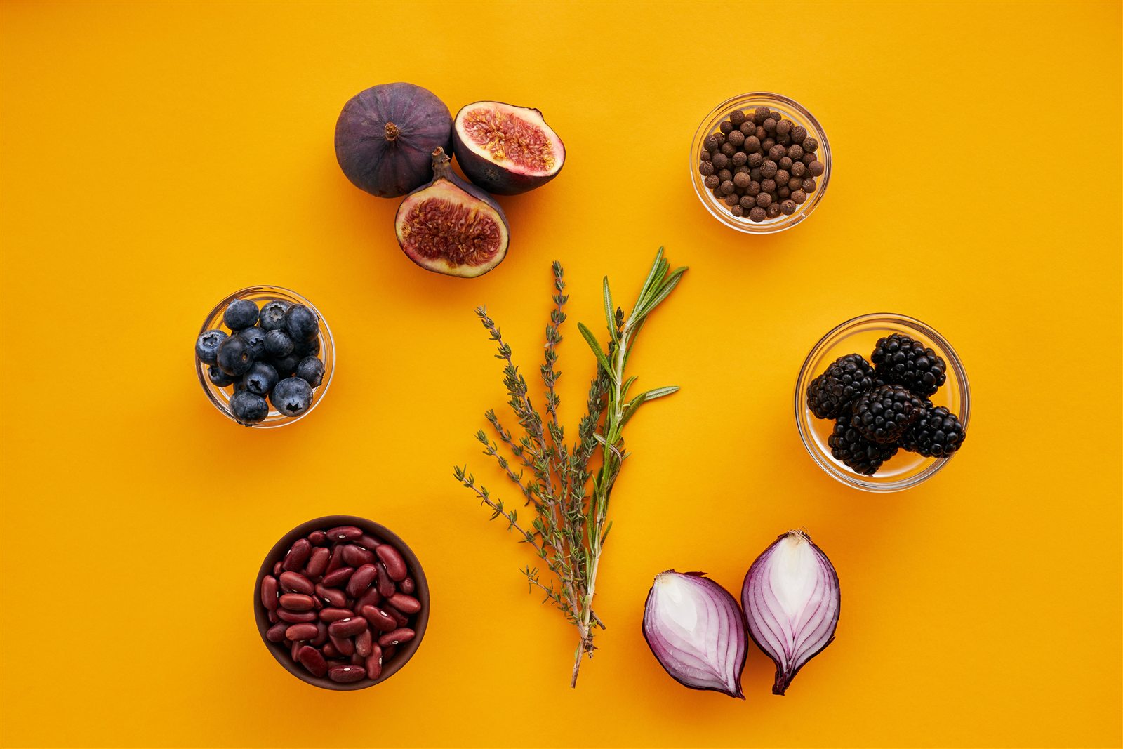 Frutos, leguminosas y hierbas aromáticas sobre fondo amarillo